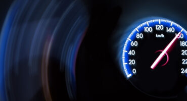 Close-up of a speedometer reading around 170 km/h with motion blur in the background.