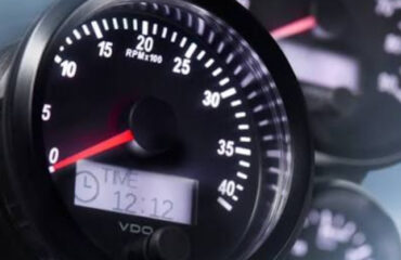 Chomu varto obyraty oryhinalne obladnannya VDO ta Lontex poyasnennya ekspertiv Tavido Close-up of a car tachometer with a red needle near 0 RPM and a digital clock reading 12:12 on the display likely from the dashboard.