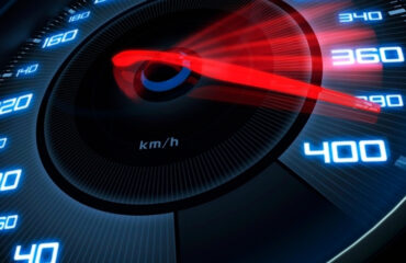 Ohlyad tsyfrovykh spidometriv dlya vantazhivok u 2026 rotsi Close-up of a car speedometer showing a red needle near 400 km/h in a blue-lit dial, emphasizing high speed.