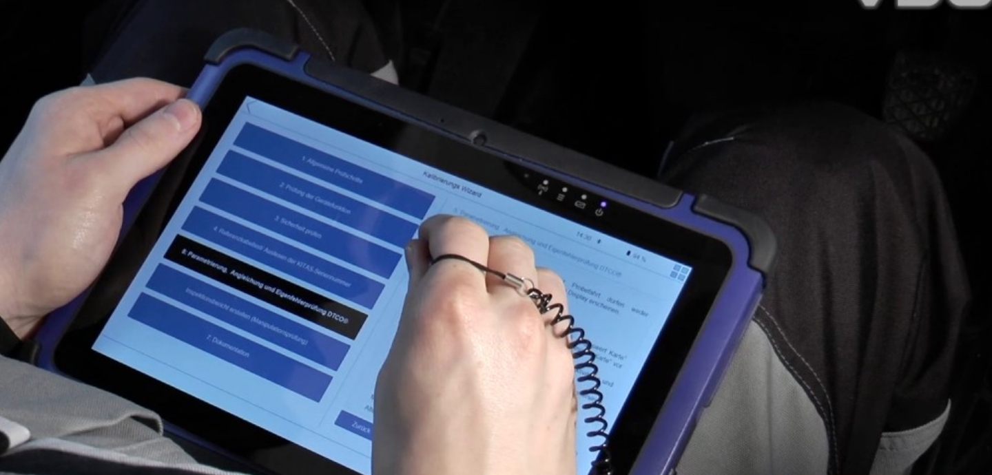 WorkshopTab 2 vid VDO novyy standart u kalibruvanni takhohrafiv Person using a stylus to interact with a blue-screen tablet in a rugged purple case, selecting menu items.