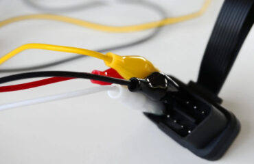 Yak pidklyuchyty takhohraf do CAN-shyny transportnoho zasobu Close-up of a wiring harness with yellow, red, and white wires connected to a black multi-pin connector.